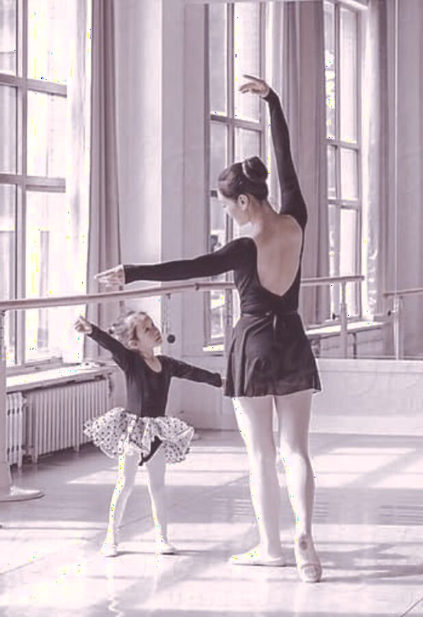 Instructor teaching a young student proper arm position at the barre